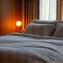 A cozy bedroom bathed in soft, warm light, with undisturbed bed linens, representing sleep and recovery